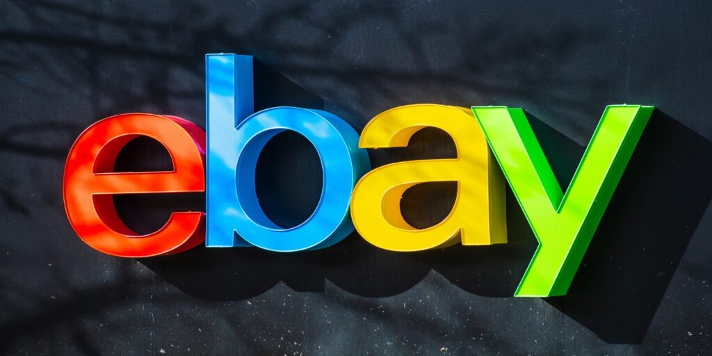 Colorful "eBay" sign against a dark background, featuring red, blue, yellow, and green letters.