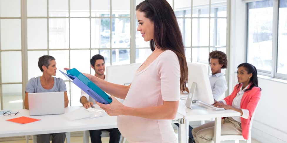 A pregnant businessperson working in a modern office.