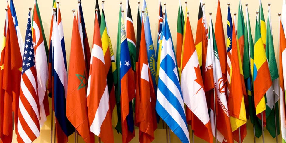 A row of different country flags standing upright against a wall.