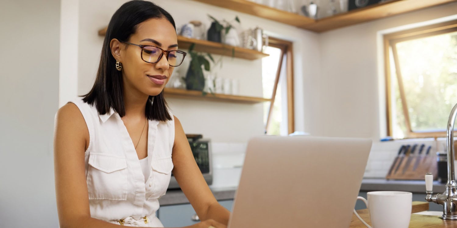 Sole trader working on a laptop in a bright kitchen, thoughtfully considering whether to transition to forming a limited company