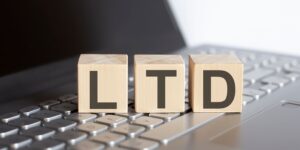 Wooden blocks spelling "LTD" placed on a laptop keyboard, symbolising the setup of a limited company