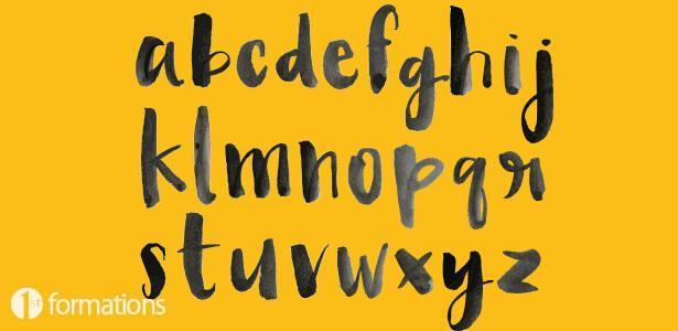 the alphabet drawn in black water colour paint on a yellow background