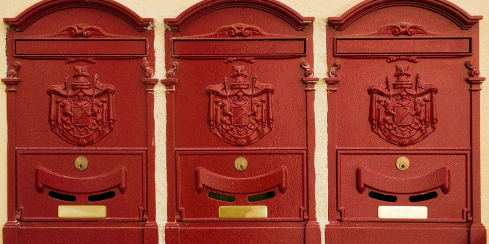 An image of three red Victorian Royal Mail post boxes mounted on a wall, representing the primary purpose of a registered office as a postal address.