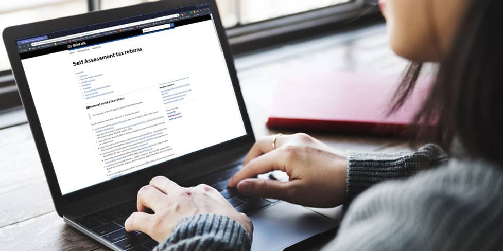 Image of a woman reading official Self Assessment guidance on her laptop