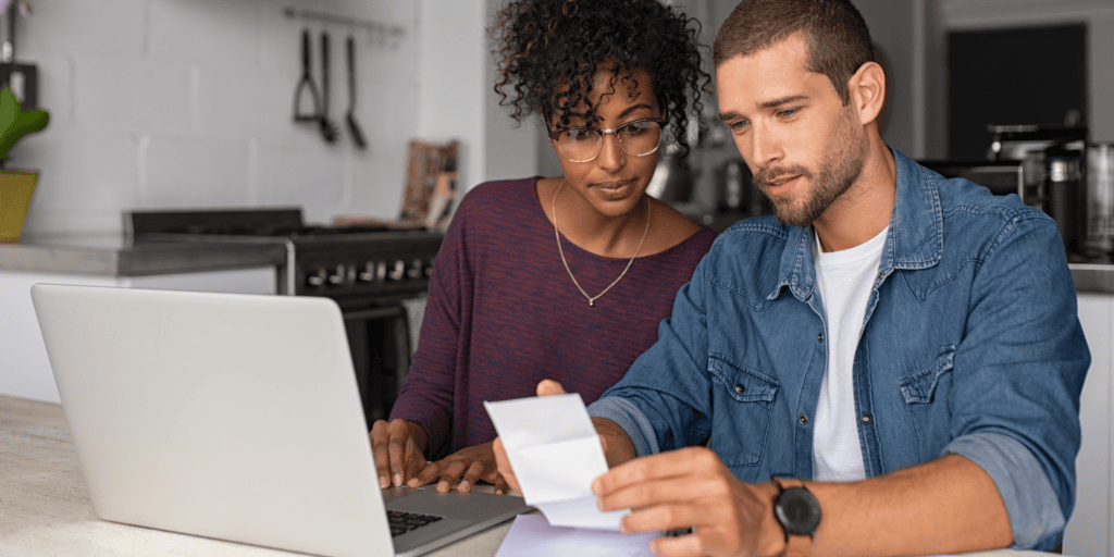 Two business owners check a receipt against their laptop as they claim business expenses.