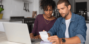 Two business owners check a receipt against their laptop as they claim business expenses.