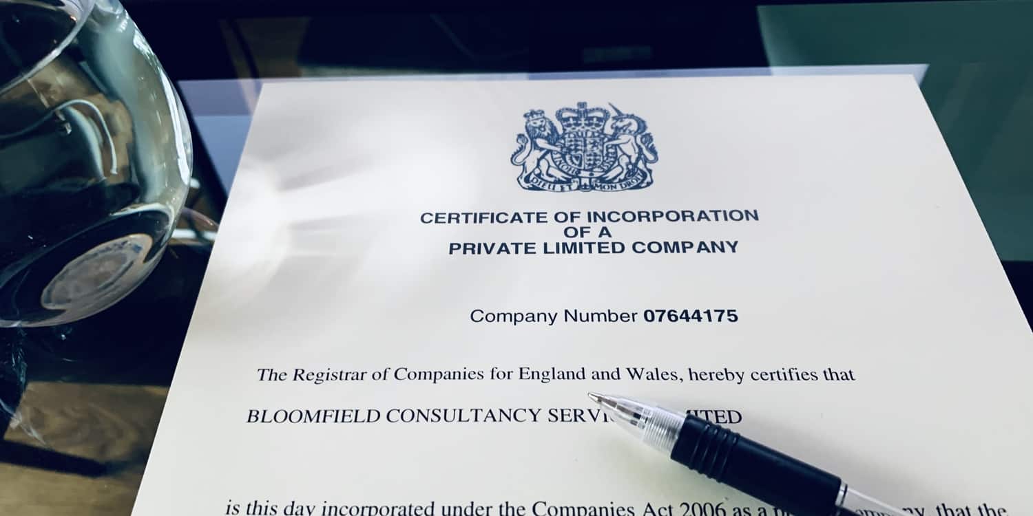 A certificate of incorporation lying on a desk with pen and glass of water.