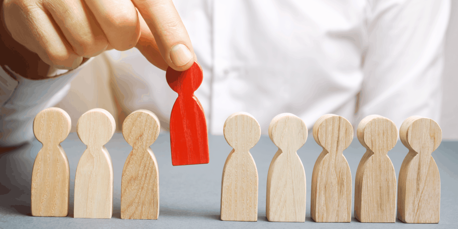 Line of wooden men with a hand lifting one, demonstrating the concept of appointing or removing a director.