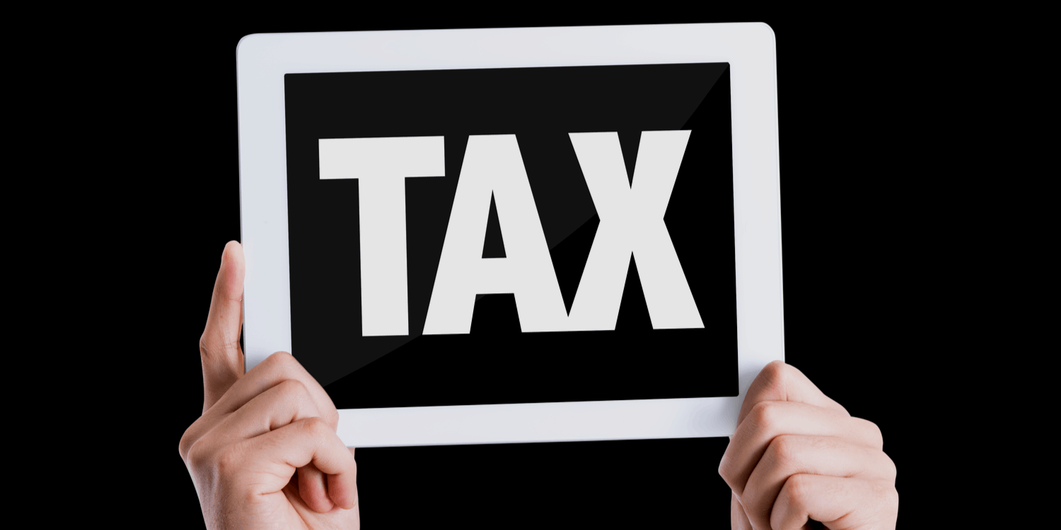 Two hands holding a sign displaying the word TAX with black background.