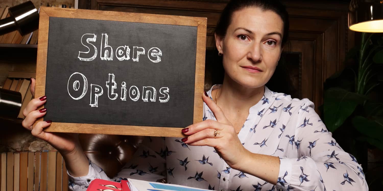 Image of a female employee holding up a blackboard with 'Share Options' displayed in white chalk.