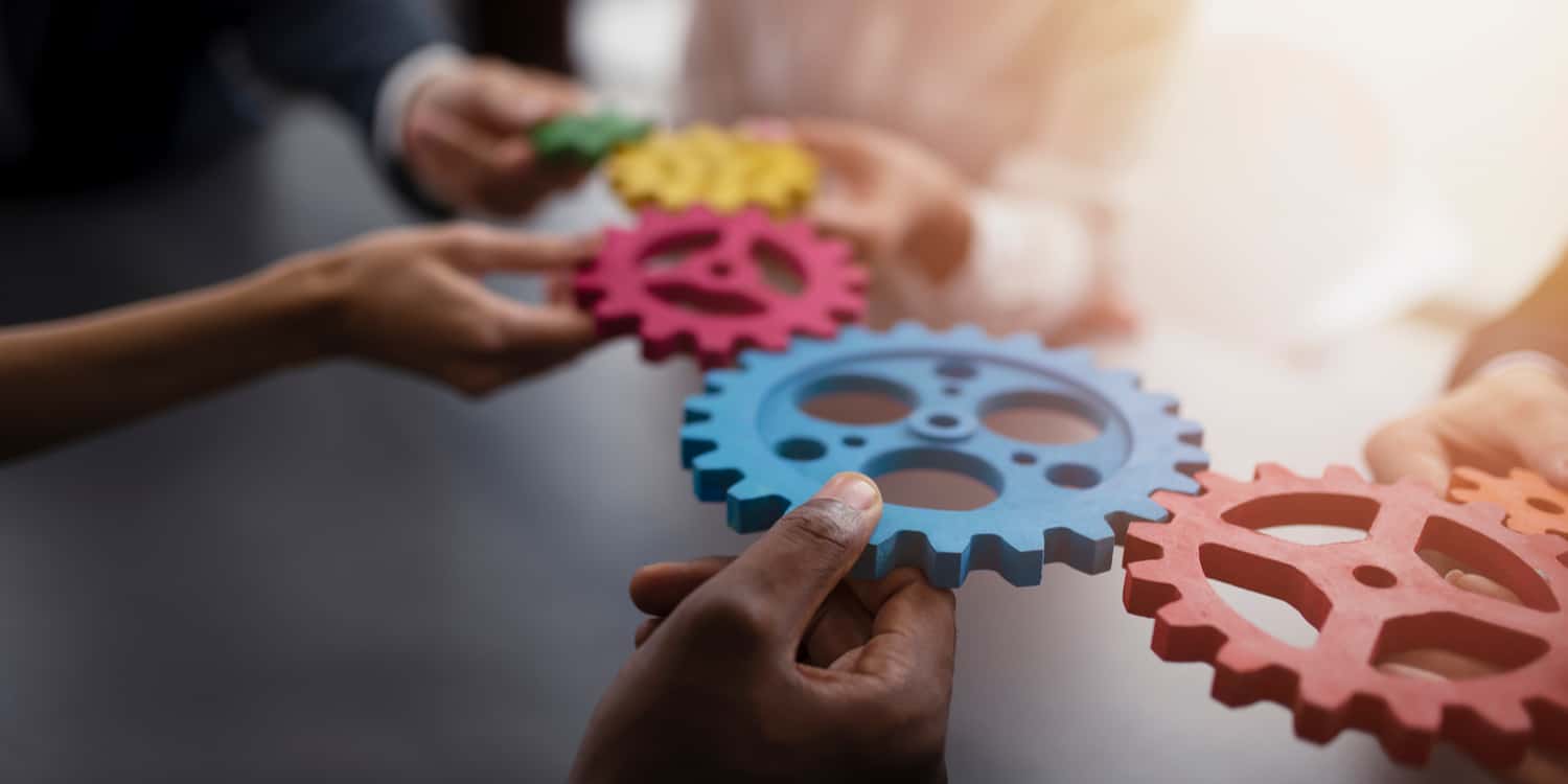 People holding coloured cogs that are touching