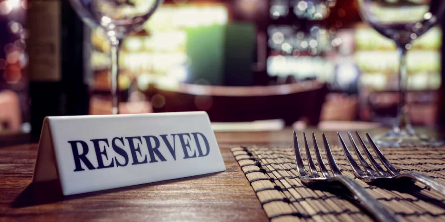 Restaurant table set for dinner with 'RESERVED' sign on it