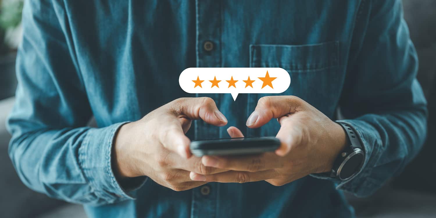 Person holding phone with graphic of speech bubble, displaying 5 gold stars