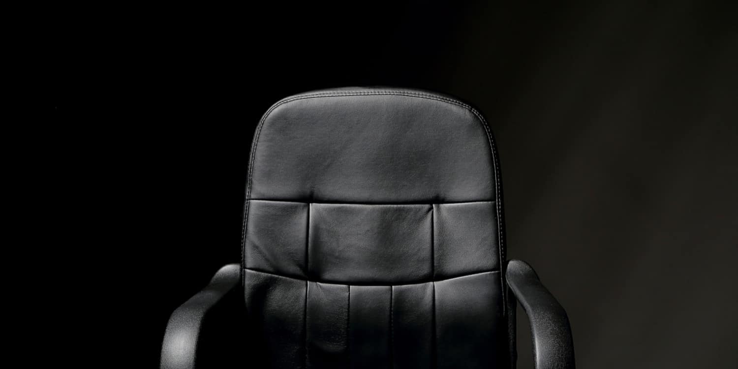 Empty black leather seat on black background