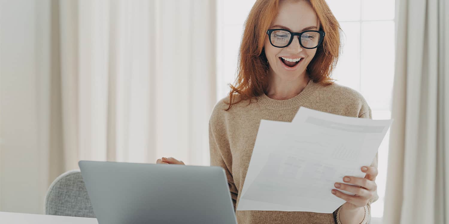 Female busienss owner with red hair and glasses overjoyed at seeing savings in her energy business energy bill.