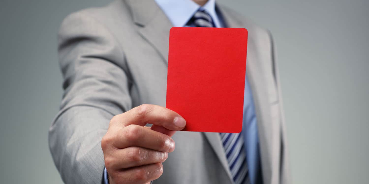 Businessman holding out a red card illustrating the concept of disqualifying a company director.