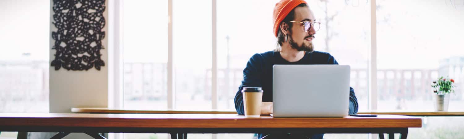 Freelance copywriter working with laptop in coffee shop.