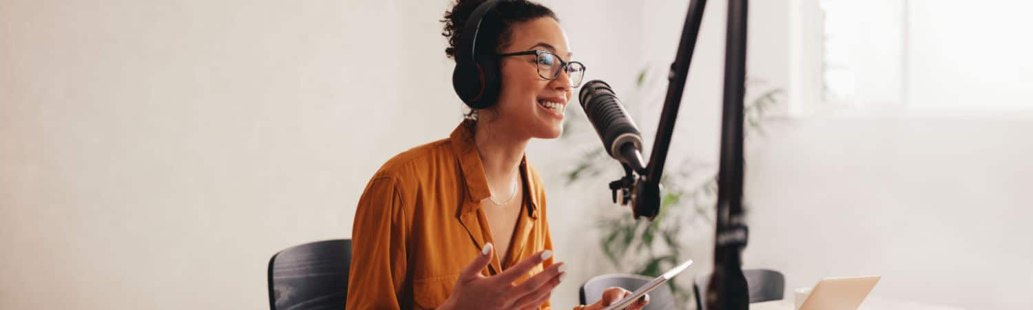 Female podcaster making audio podcast from her home studio, illustrating podcasting as one of the top 10 businesses to start in 2023.