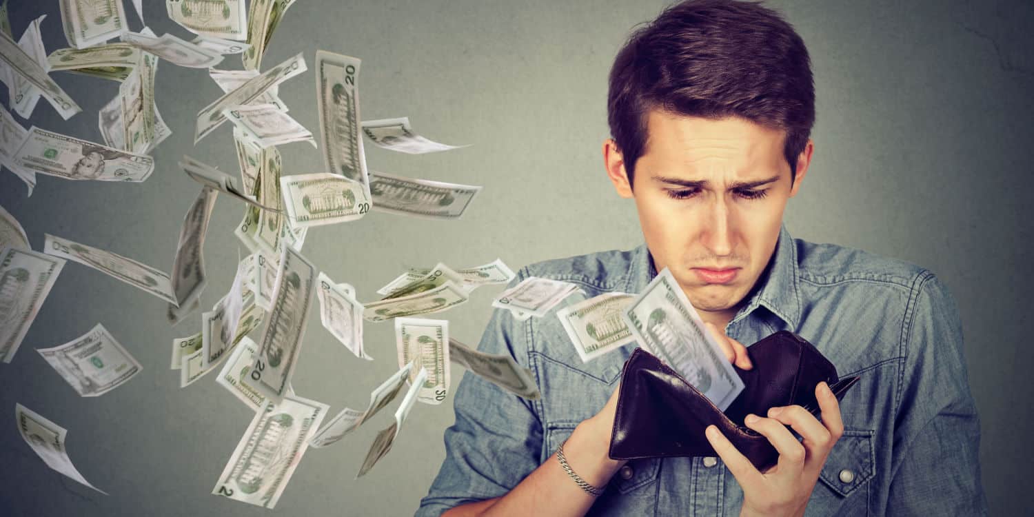 Sad man looking at his wallet with money banknotes flying out and into the air. Concept of pre-trading expenses.