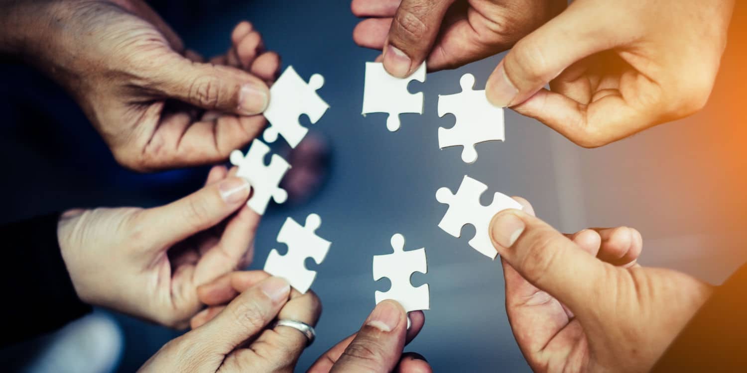 Close-up photo of hands each holding a jigsaw piece, illustrating the concept of joint shareholders.