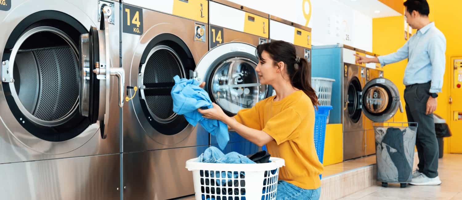 People using coin operated laundry machine in laundrette.