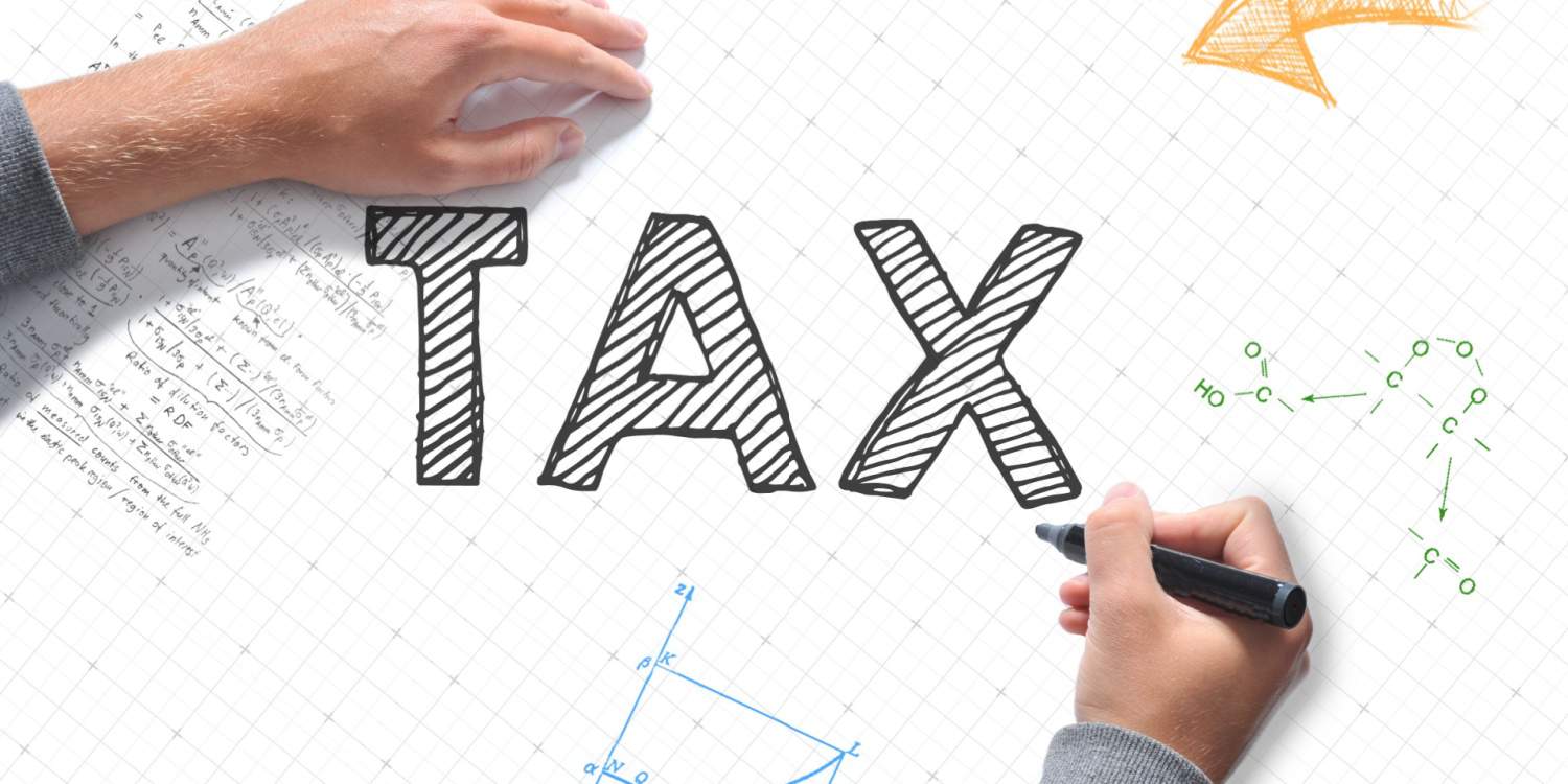 Male hands writing TAX on a white sheet of paper with a large black marker pen.
