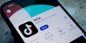 TikTok app page displayed on a smartphone screen, showing the app icon, age rating, and a blue "Open" button.