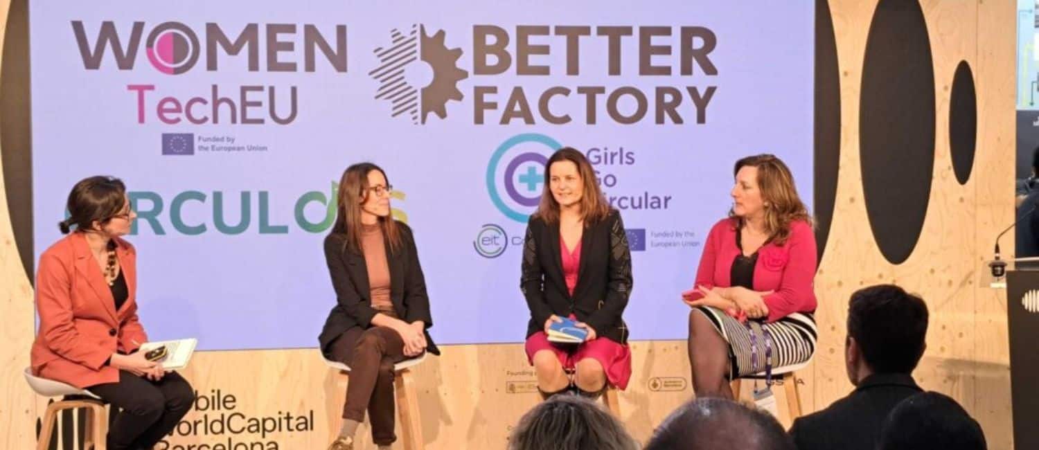 A panel of four women sitting on stools and having a discussion on a stage at a Women TechEU event. A screen can be seen behind them, featuring several logos, including Women TechEU and Better Factory.