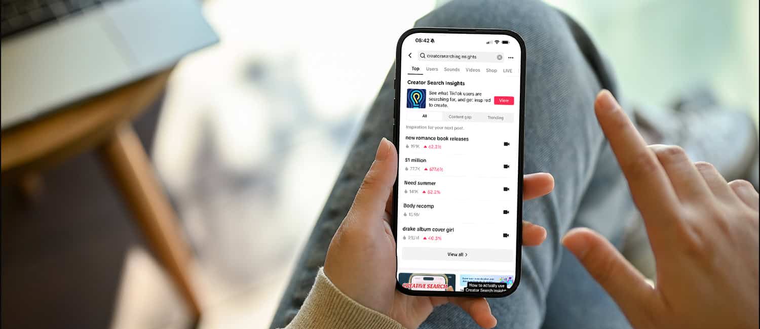 A person holds a smartphone displaying TikTok's Creator Search Insights, showcasing trending topics and user data.
