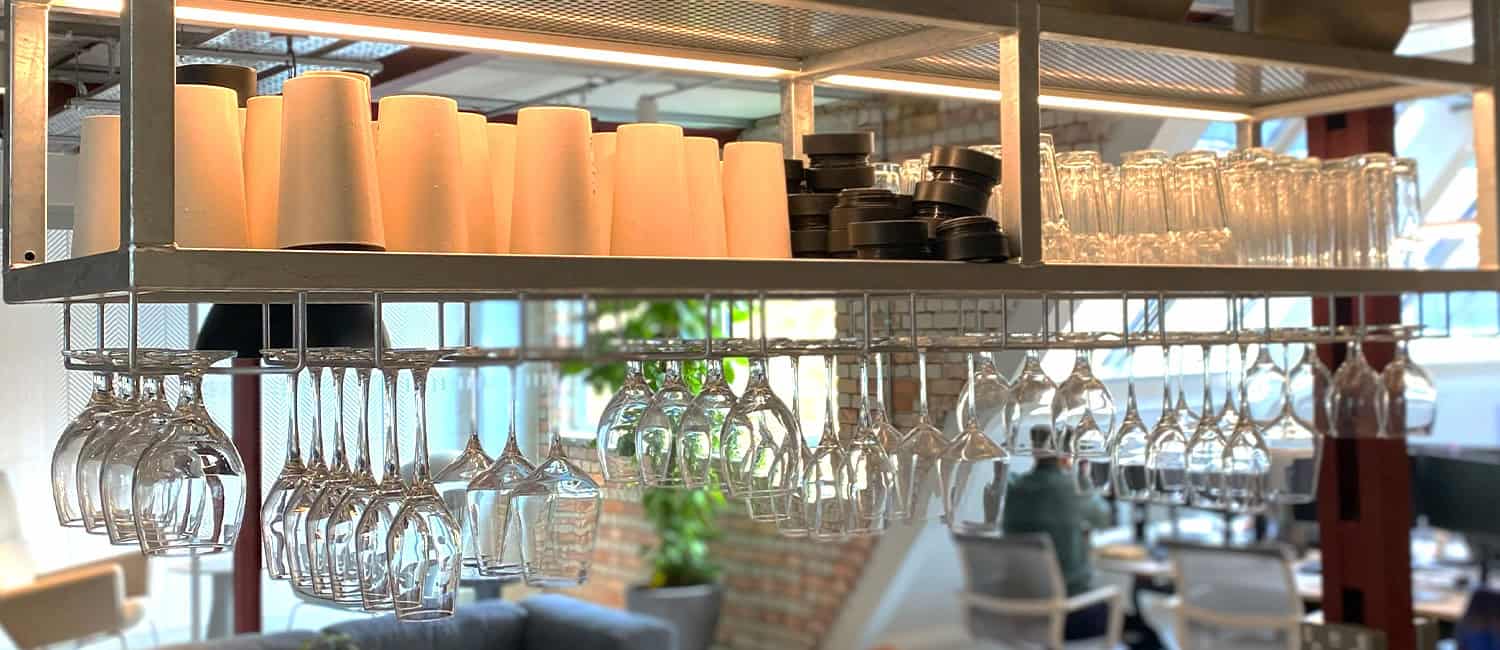 Glassware and reusable bamboo cups neatly arranged on a kitchen counter in a modern office space