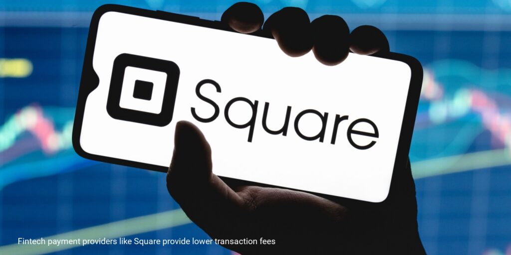 A male hand holding a smartphone with the Square logo on the screen.