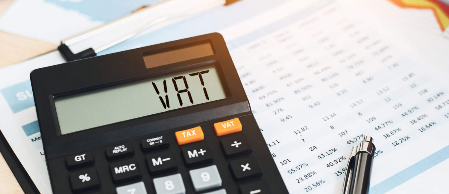 'VAT' displayed on a calculator sitting on an accountant's report.