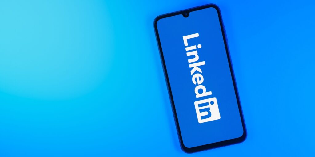 Smartphone showing LinkedIn logo against a blue background.