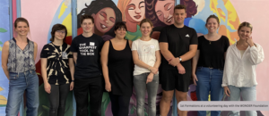 1st Formations staff standing together during a business volunteering day with the charity WONDER Foundation, in front of a colourful mural painted as part of the initiative