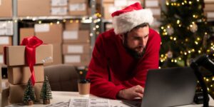 A man in a festive hat working on a laptop, preparing his business for Christmas