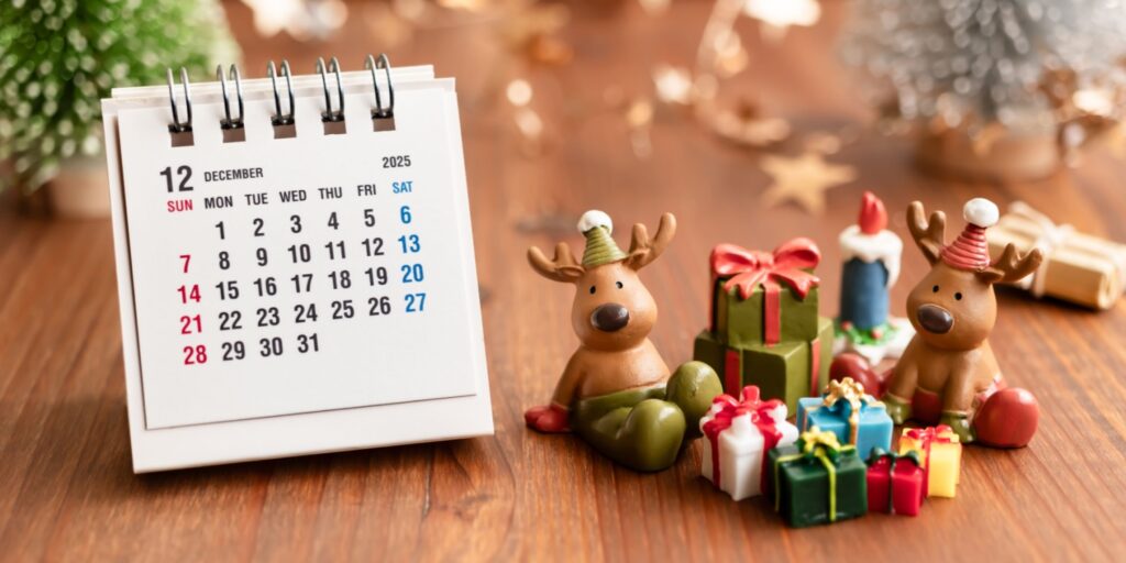 December 2025 desk calendar surrounded by festive holiday decorations and gift boxes, representing Q4 business and marketing dates 2025