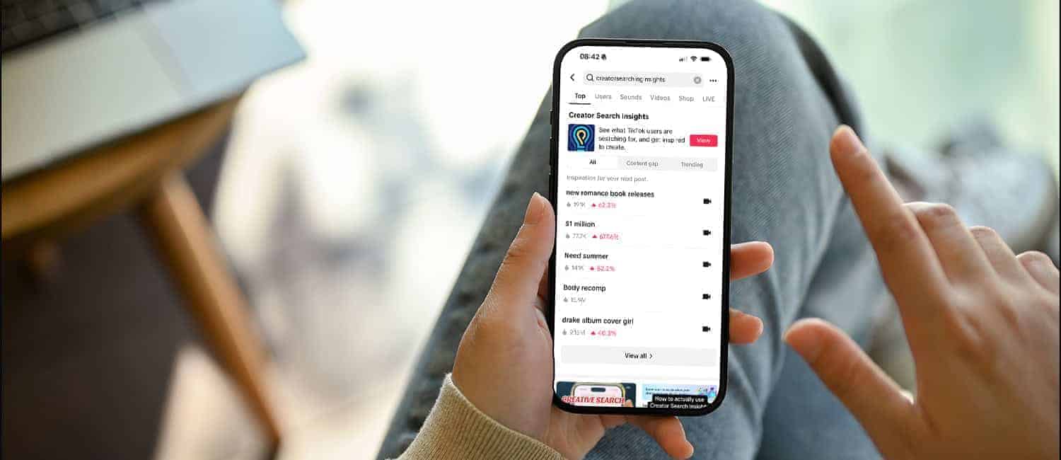 A person holds a smartphone displaying TikTok's Creator Search Insights, showcasing trending topics and user data.