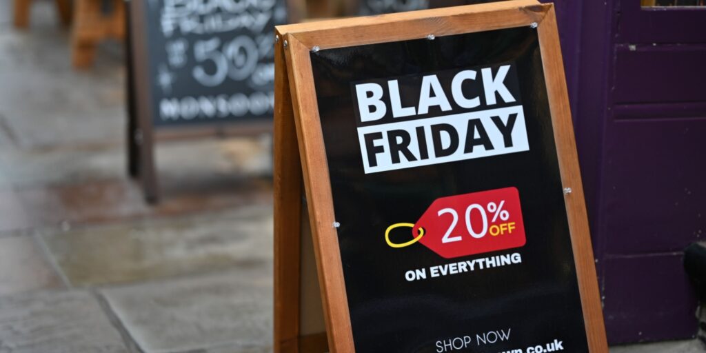Black Friday marketing business promotion displayed on a pavement sign outside a shop, featuring bold text offering 20% off everything as part of a seasonal sales campaign