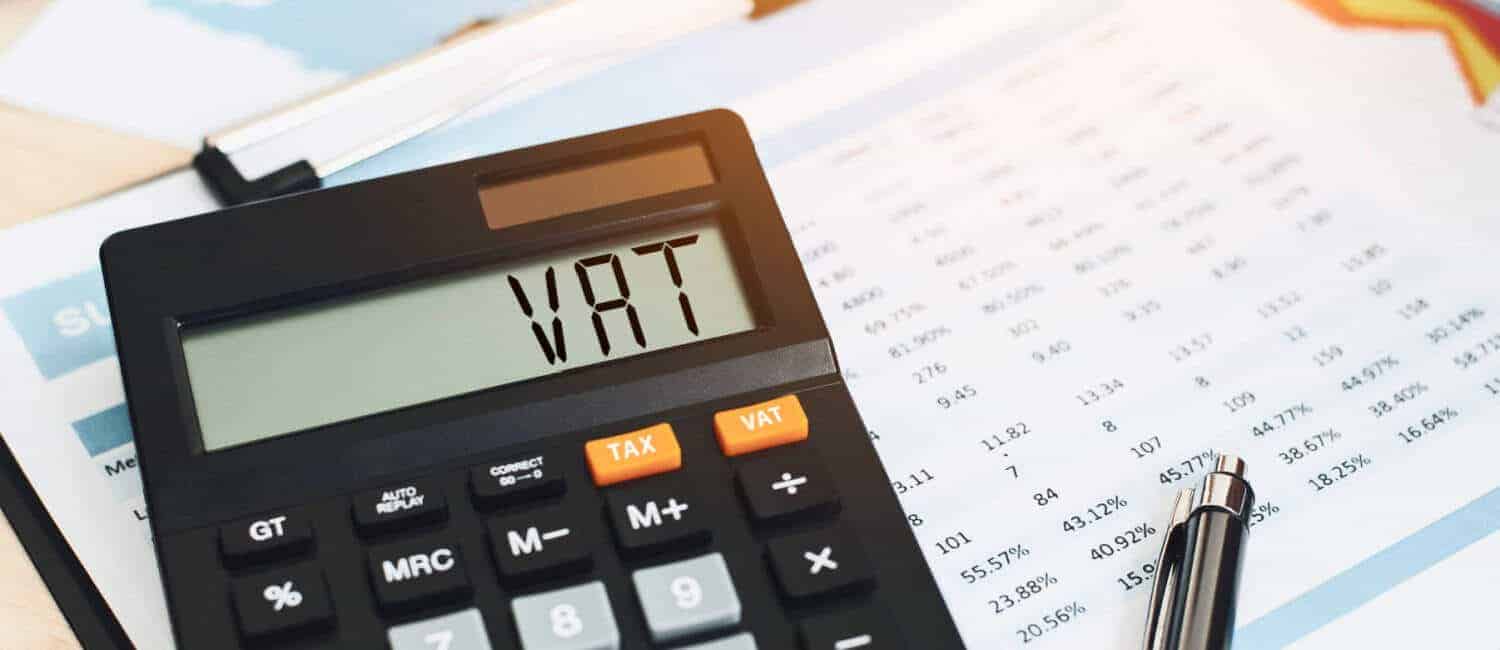 'VAT' displayed on a calculator sitting on an accountant's report.