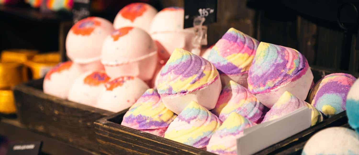Handmade bath bombs laid out in a pyramid on a store counter.