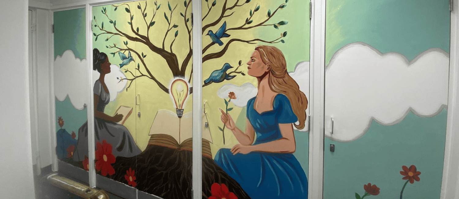 An uplifting mural featuring two women facing each other, one is holding a rose and the other a book. They are both in nature, with a tree glowing in the background.