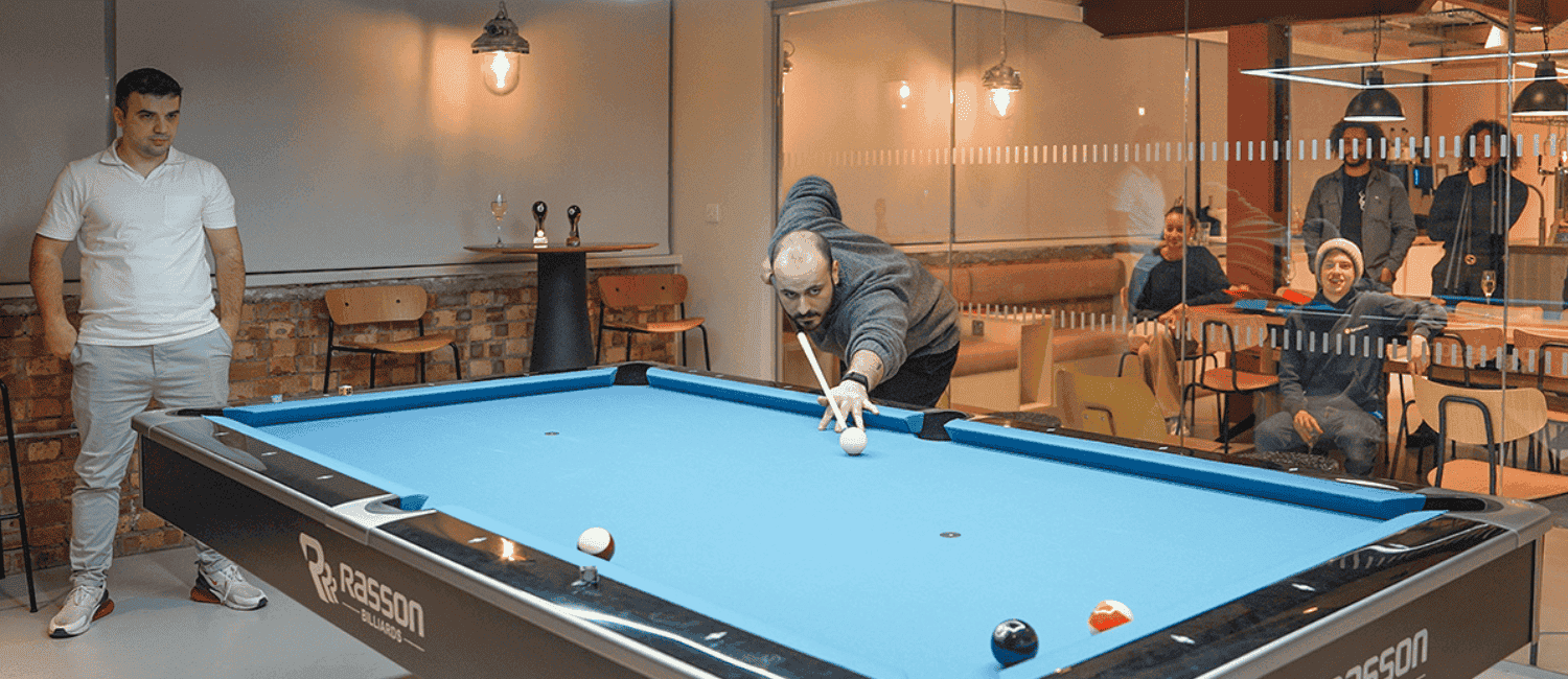 Two people playing pool in the 1st Formations office.