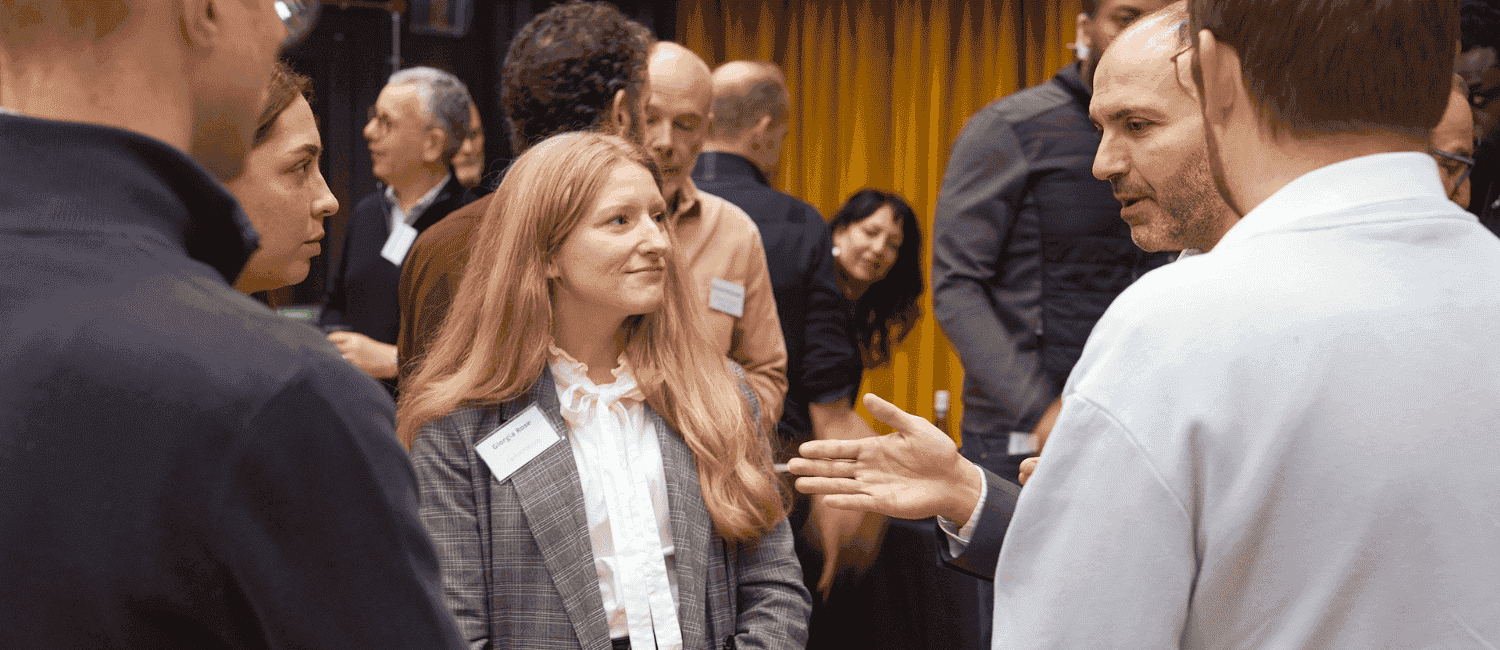 1st Formations employees networking at an ASTOP event. They are in a hall and talking with other business professionals about CSR and Business Rates.