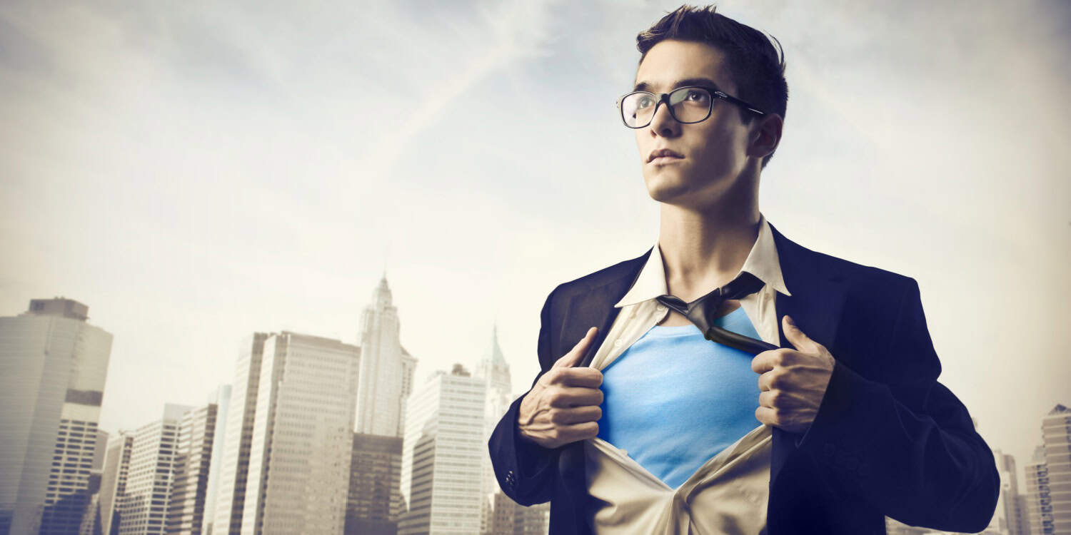 Man in business attire pulling open shirt to reveal superhero-style costume, symbolising inner strength.