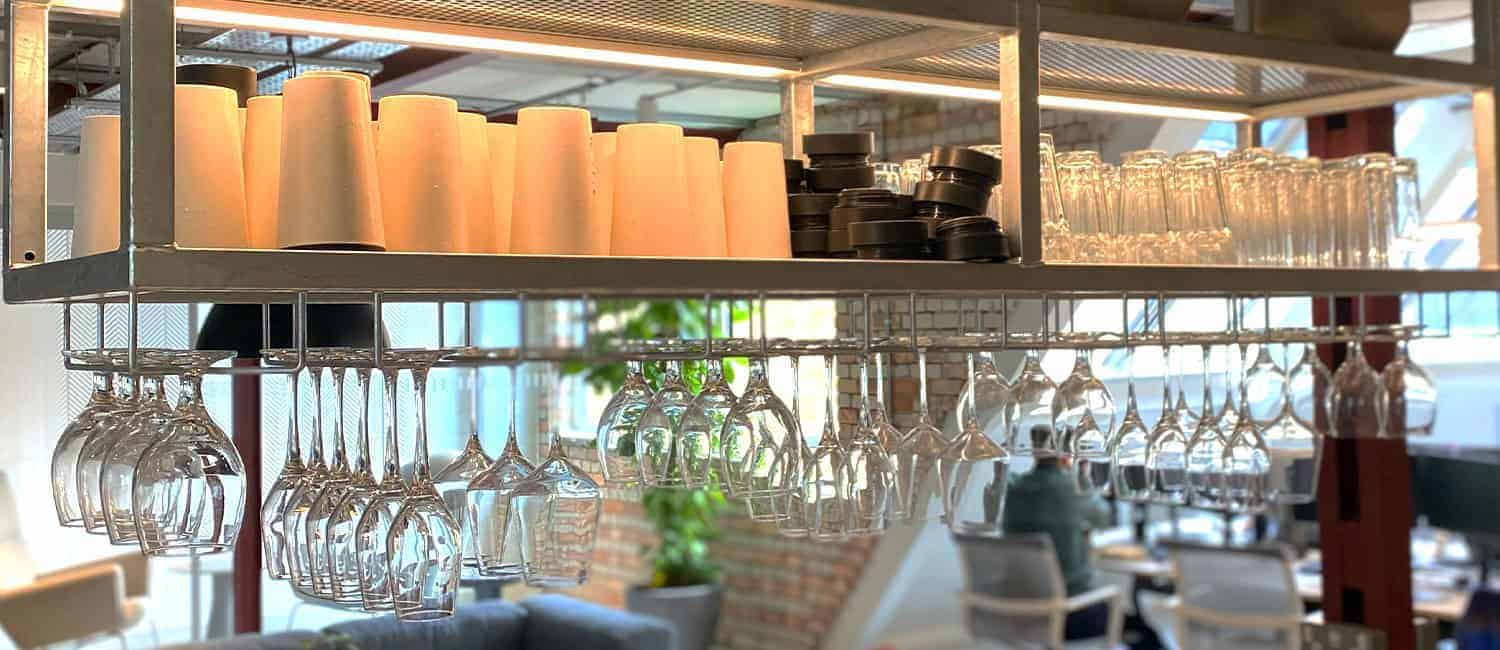 Glassware and reusable bamboo cups neatly arranged on a kitchen counter in a modern office space