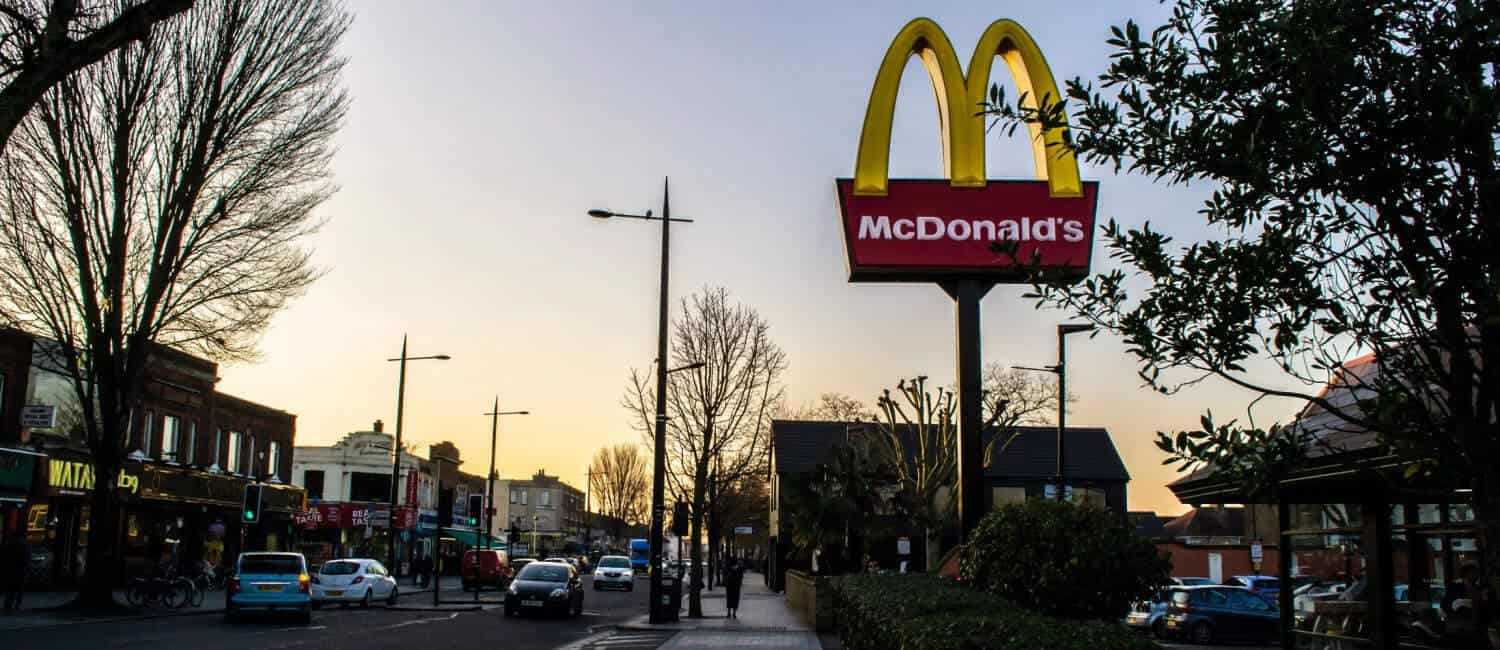 McDonald's sign for a restaurant in the UK, set against a sunset with trees