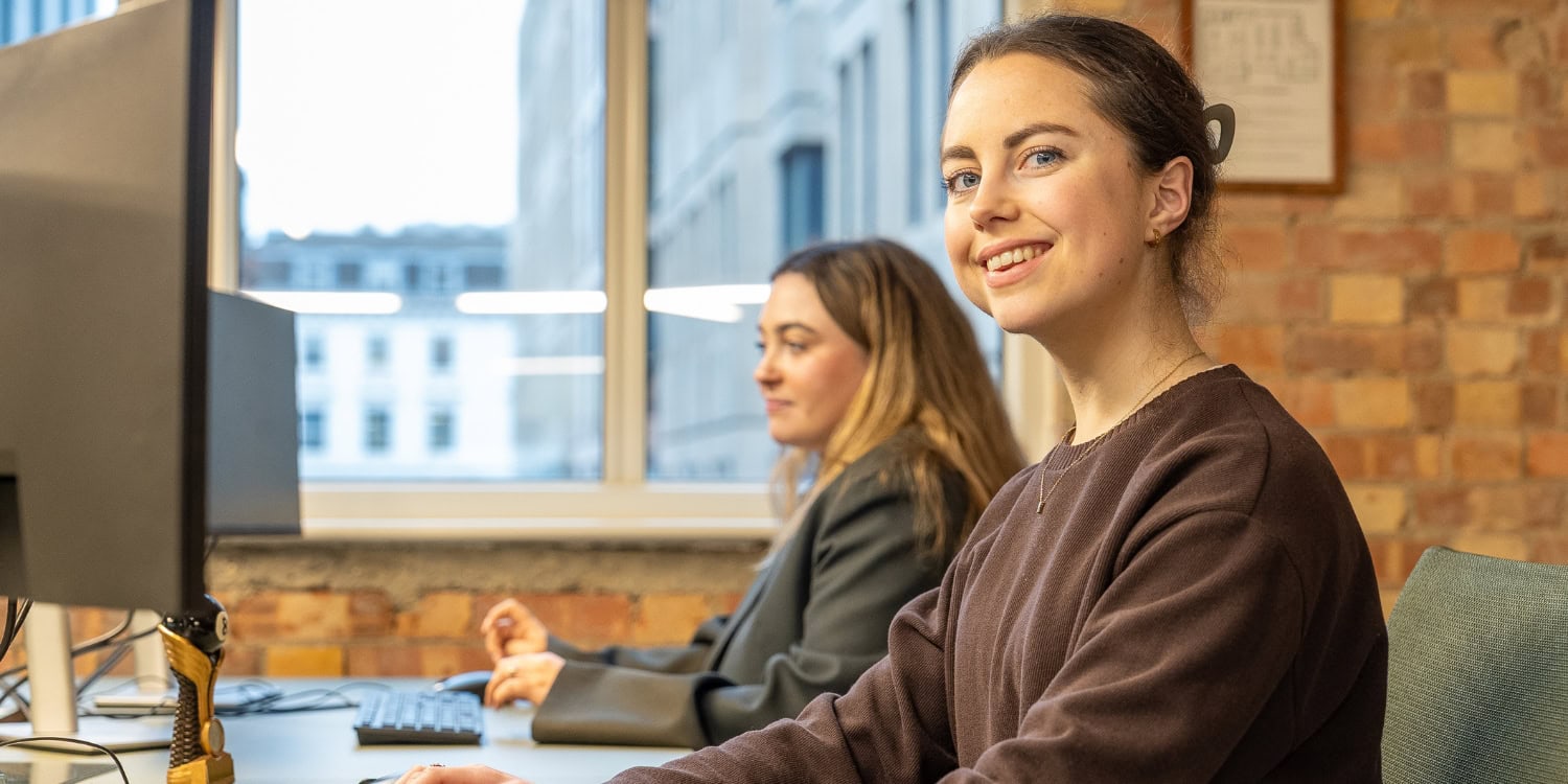 Two women working at computers in a modern office.