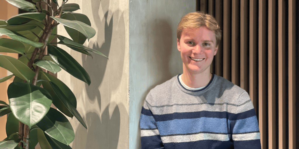 Cyril Estier, Founder and CEO of Arti, smiling in a casual blue striped jumper beside a large indoor plant against a concrete wall