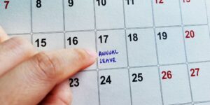 A finger pointing at a calendar, to the 17th of the month, where it says 'Annual Leave'.